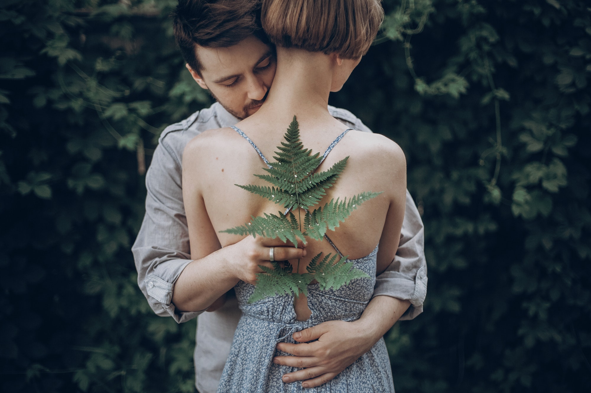 stylish-hipster-bride-and-groom-embracing-in-green-leaves-forest-man-kissing-woman-neck.jpg